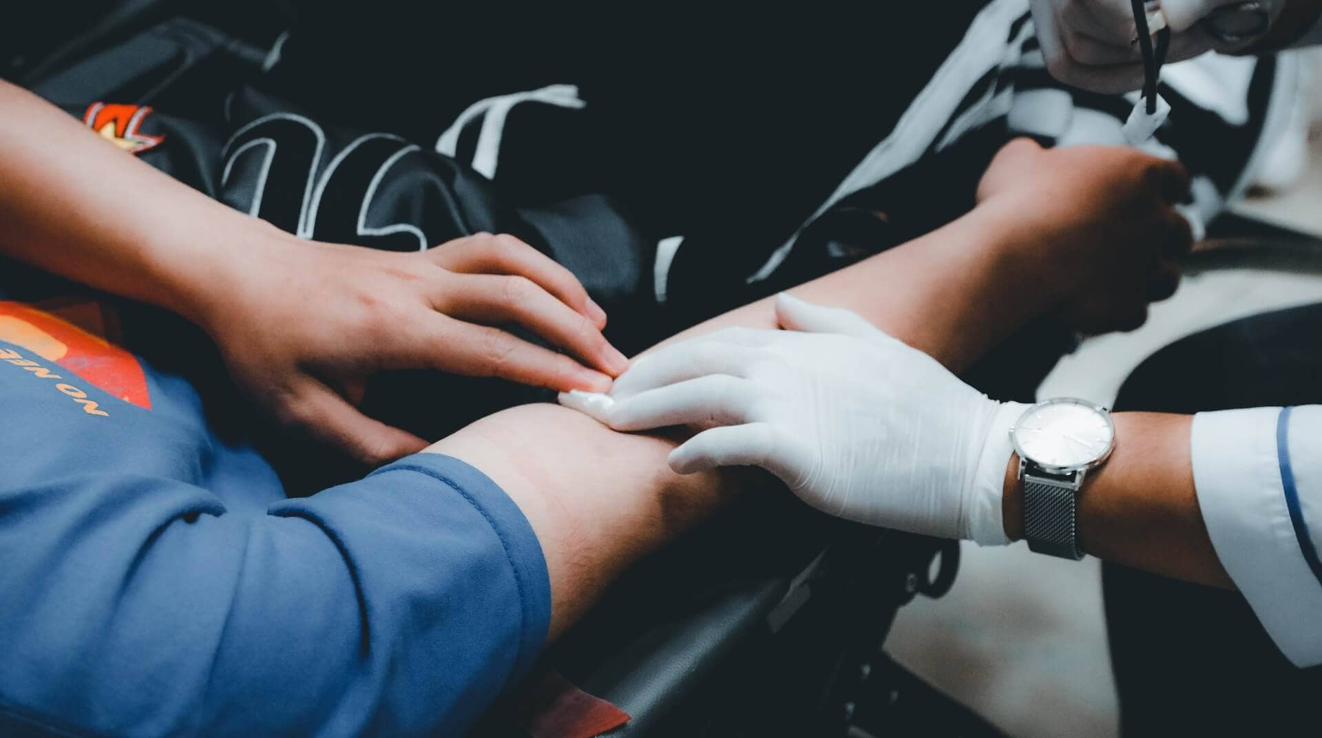 A healthcare professional pressing on a person's arm after having taken blood from them for a test