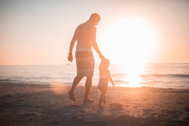 A man with a child walking on the beach